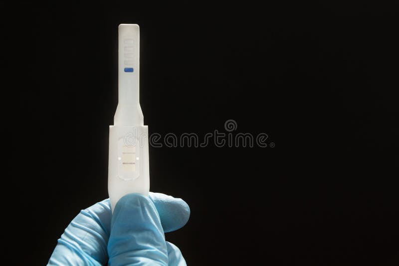 Succesvolle kunstmatige inseminatie De positieve zwangerschapstest met twee stroken in dient een blauwe medische handschoen op ee stock afbeelding Succesvolle kunstmatige inseminatie De positieve zwangerschapstest met twee stroken in dient een blauwe medische handschoen op ee stock afbeelding