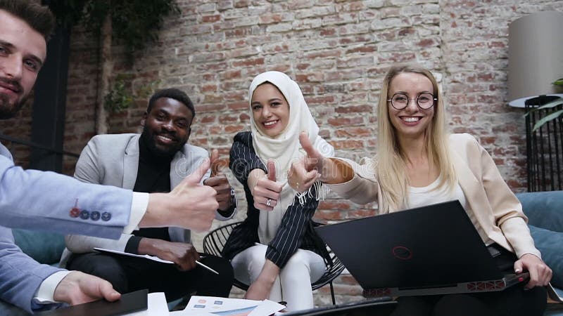 Succesvolle multi-etnische groep zakenmensen met een arabische vrouwelijke leider in hijab die een gebaar met duimen tonen, kijke