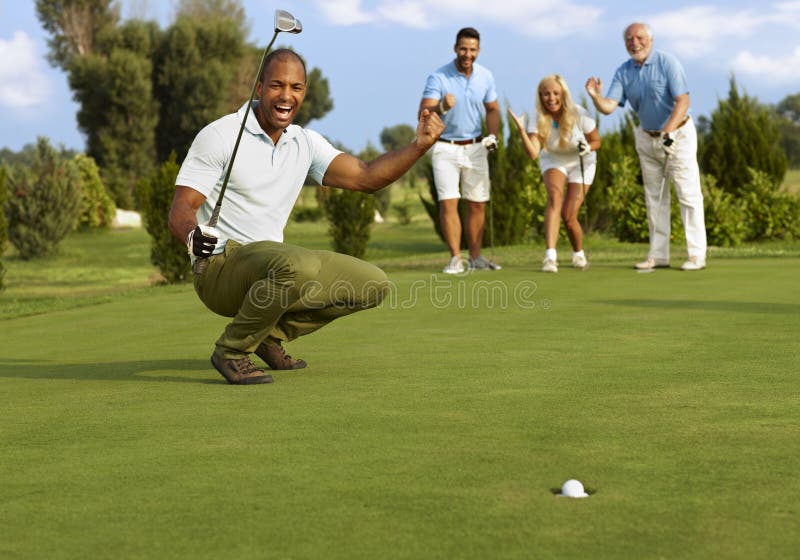 Male golfer and partners happy for successful putt on the green. Male golfer and partners happy for successful putt on the green.