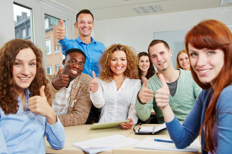 Successful students holding their thumbs up with teacher in classroom. Successful students holding their thumbs up with teacher in classroom