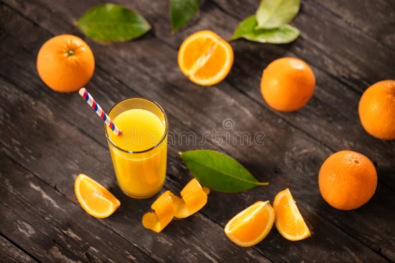 Succo d'arancia di recente schiacciato con le mezze arance sulla tavola di legno fotografia stock Succo d'arancia di recente schiacciato con le mezze arance sulla tavola di legno fotografia stock