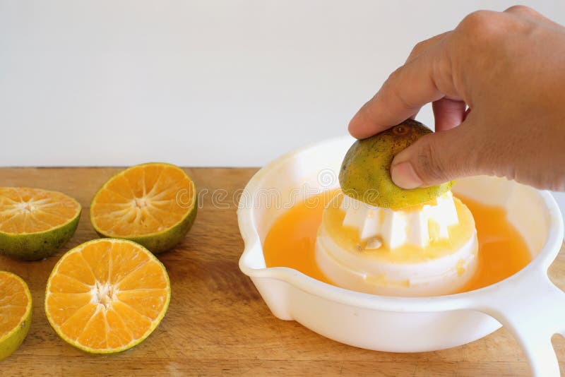 Succo d'arancia juicing della mano su fondo bianco fotografia stock libera da diritti Succo d'arancia juicing della mano su fondo bianco fotografia stock libera da diritti