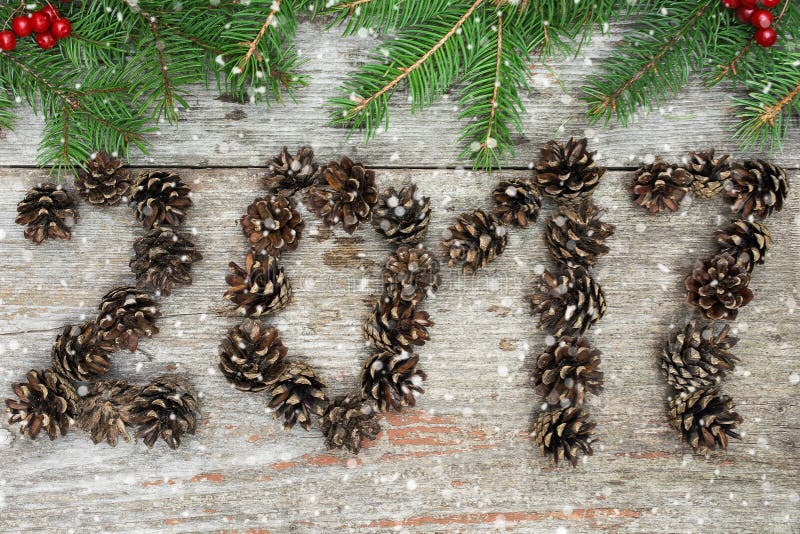 Sigh symbol from pine cones number 2017 on old retro vintage wooden texture with christmas tree branches and red berries. happy new year concept. Sigh symbol from pine cones number 2017 on old retro vintage wooden texture with christmas tree branches and red berries. happy new year concept