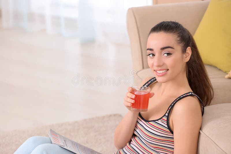 Suco bebendo do citrino da jovem mulher bonita ao ler o compartimento em casa fotografia de stock royalty free Suco bebendo do citrino da jovem mulher bonita ao ler o compartimento em casa fotografia de stock royalty free