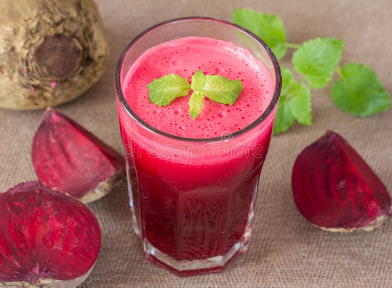 Sumo de beterraba num copo e beterrabas fotografia de stock royalty free