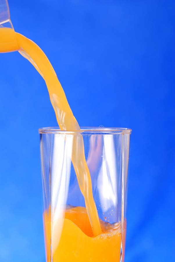 Pouring juice against blue background. Pouring juice against blue background