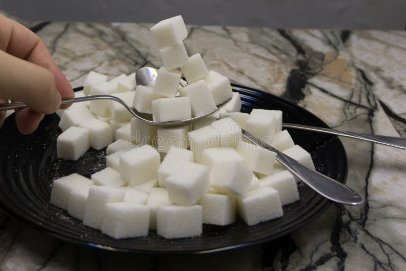Sucre avec des cuillères d'un plat noir image stock Sucre avec des cuillères d'un plat noir image stock