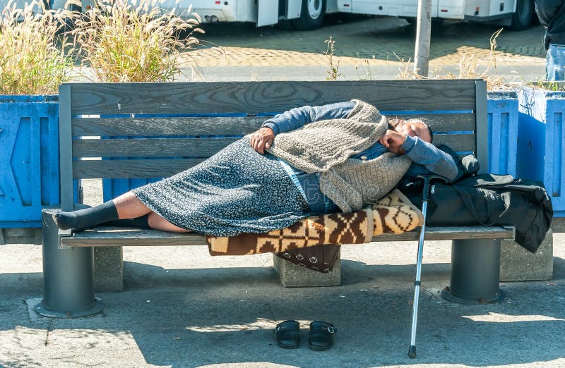 Sueño descalzo de la mujer de los desamparados en el banco de madera en la calle urbana en la ciudad en la acera imagenes de archivo Sueño descalzo de la mujer de los desamparados en el banco de madera en la calle urbana en la ciudad en la acera imagenes de archivo