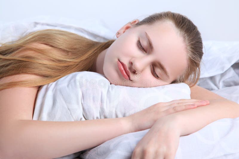 Portrait of a face with eyes closed. Teen girl sleeps lying on a pillow isolated on white background. Portrait of a face with eyes closed. Teen girl sleeps lying on a pillow isolated on white background