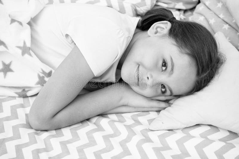 Sueños dulces El niño feliz sonriente de la muchacha pone en cama con las almohadas del modelo de estrella y la tela escocesa lin