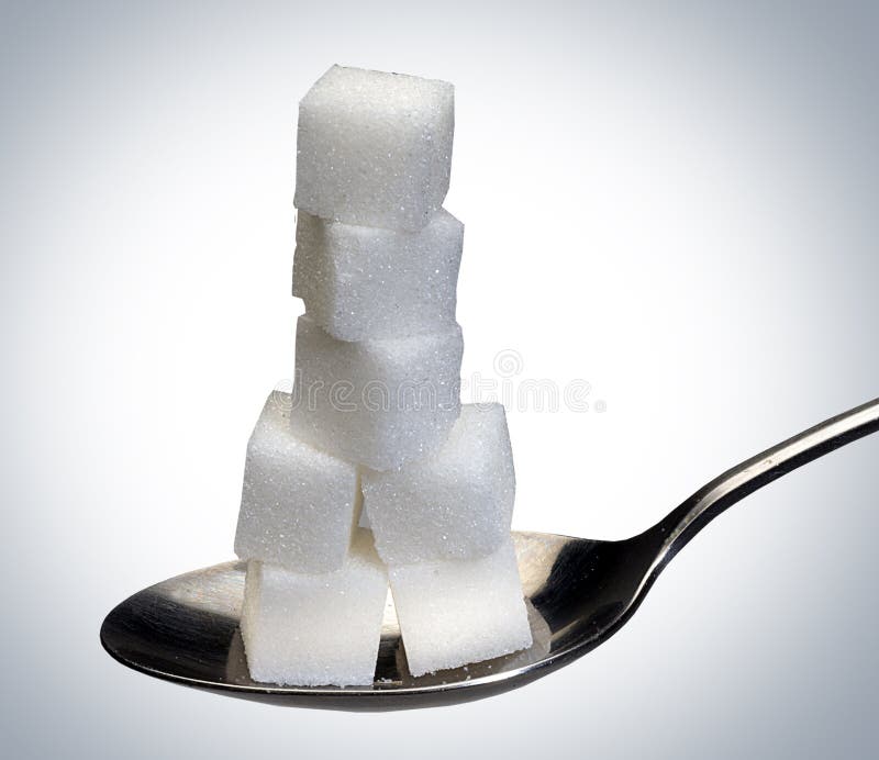 Sugar cubes stacked on spoon against white