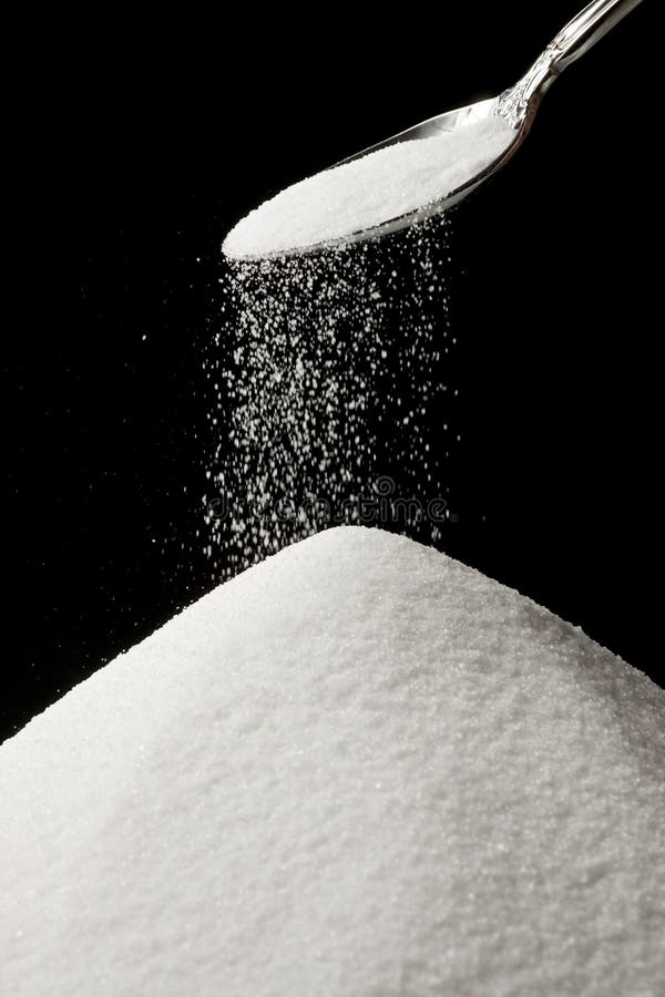 Sugar fallings from Silver Spoon. Focus on edge of spoon, sugar pile top.