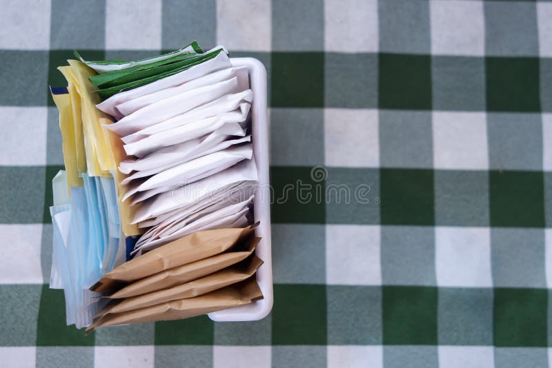 Sugar packets on a Checkered white and green table cloth