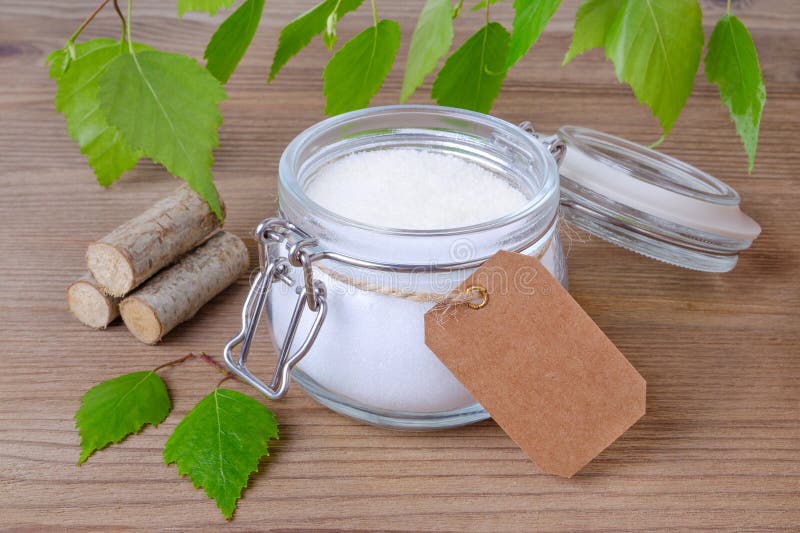 Sugar substitute xylitol, a glass jar with birch sugar and a label for text in your language on wooden background