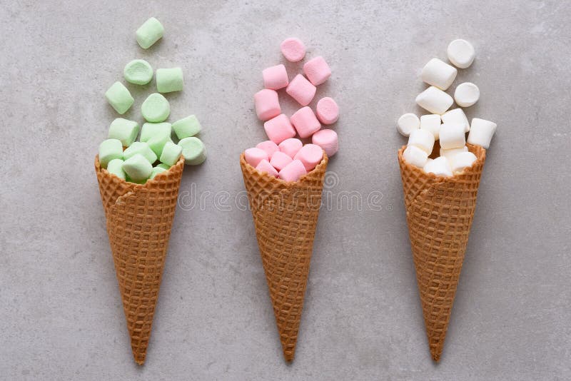 Sugar Waffle Ice Cream Cones füllte mit den bunten Eibischen, die auf Fliesentabelle verschüttet werden stockbild