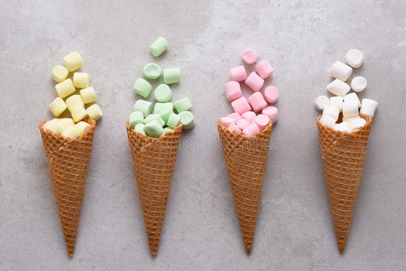 Sugar Waffle Ice Cream Cones füllte mit den bunten Eibischen, die auf Fliesentabelle verschüttet werden lizenzfreies stockbild