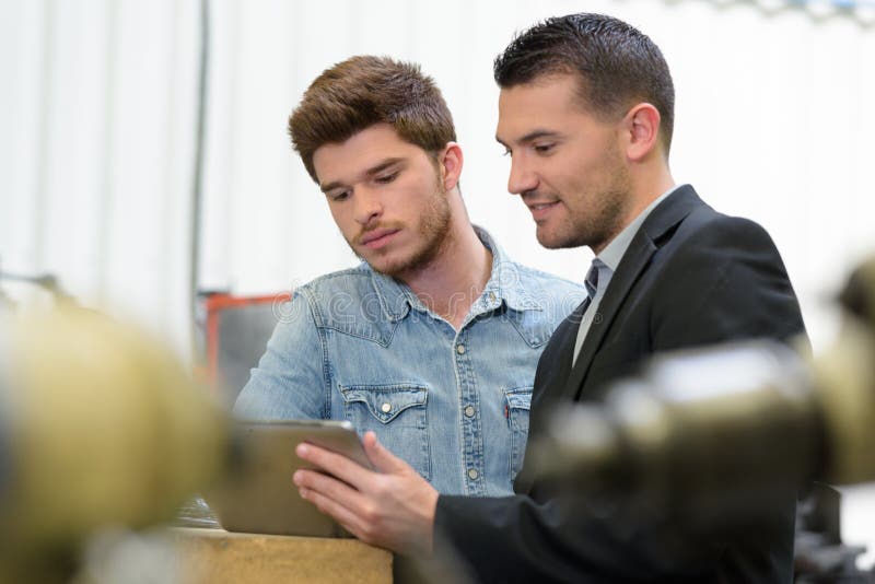 Suited manager showing tablet to unimpressed young worker royalty free stock images