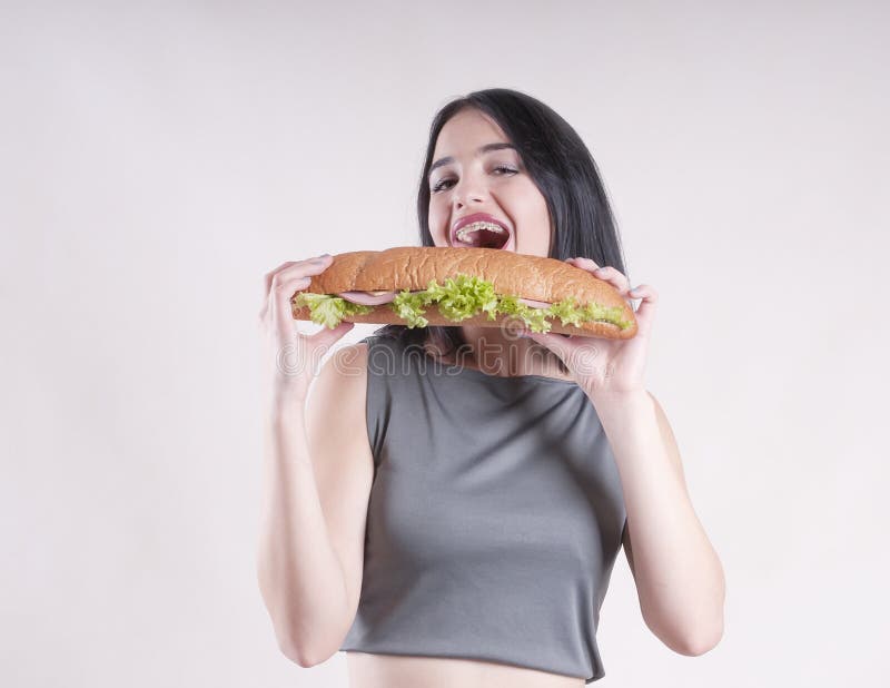 Suivre un régime heureux de beau de sports de fille de brune à consommation de sandwich studio mince de déjeuner images stock Suivre un régime heureux de beau de sports de fille de brune à consommation de sandwich studio mince de déjeuner images stock