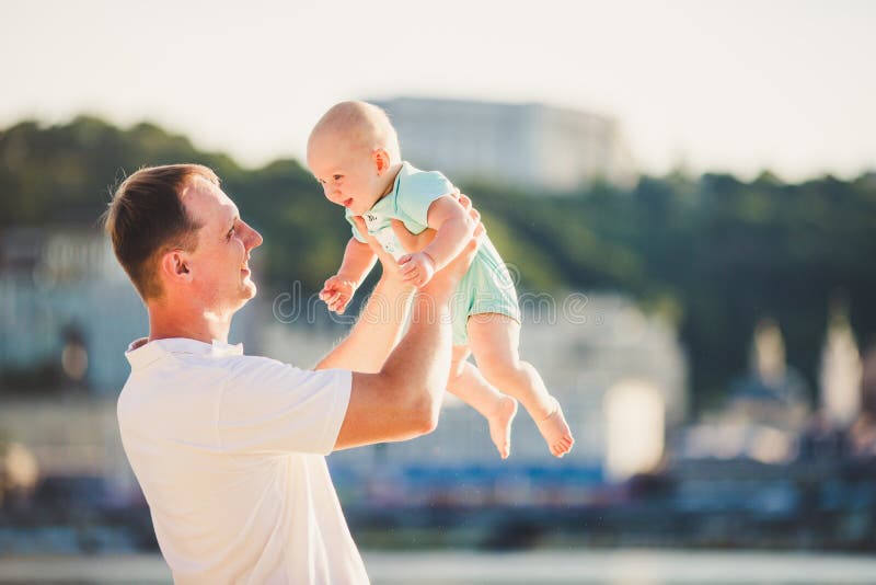 Sujeite o Parenting, as f?rias de ver?o, o pai e o filho pequeno O paizinho caucasiano novo guarda nos bra?os, cidade de neglig?n foto de stock royalty free Sujeite o Parenting, as f?rias de ver?o, o pai e o filho pequeno O paizinho caucasiano novo guarda nos bra?os, cidade de neglig?n foto de stock royalty free