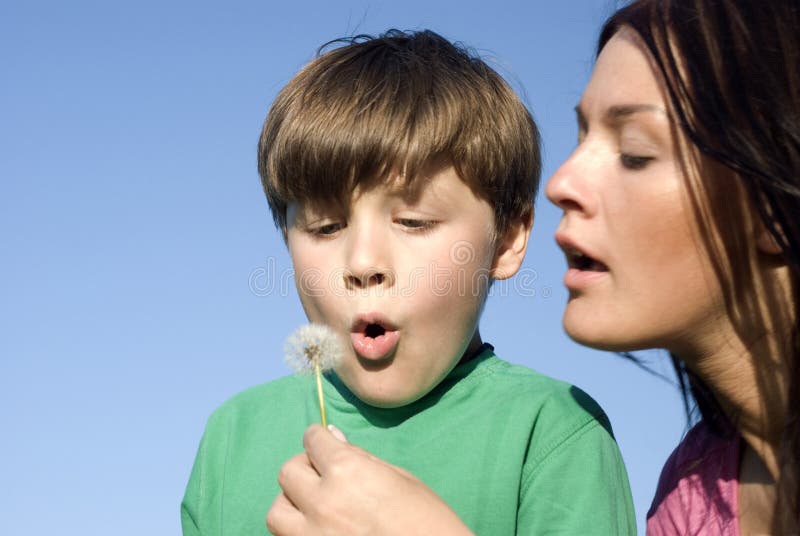 Mother and son blowing out a dandelion at the park. Mother and son blowing out a dandelion at the park