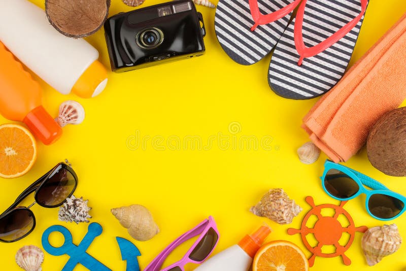 summer accessories with sun glasses, a hat, shells, flip flops, a camera on a bright yellow background. top view. space for text