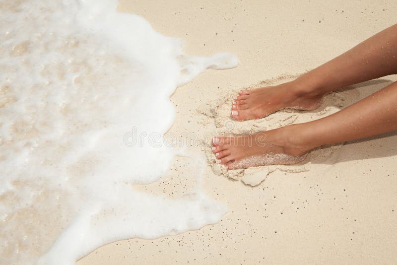 Summer beach concept. Care for beautiful woman skin and nails. Woman legs, spa therapy. Closeup photo of sandy female feet with