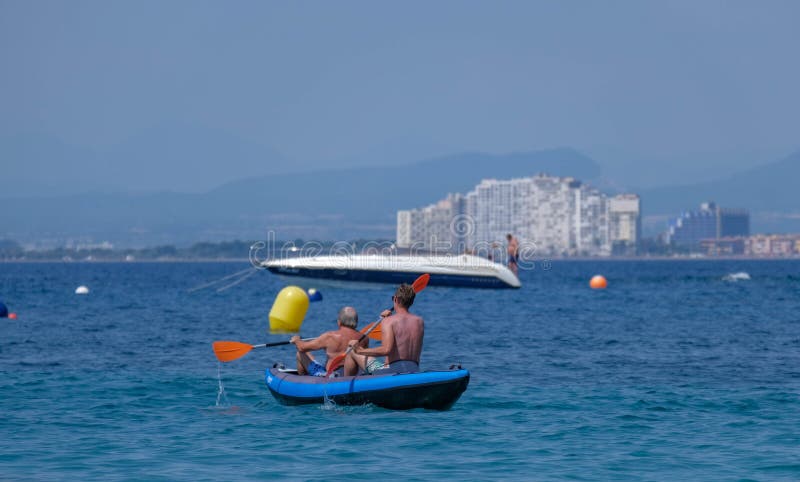 Summer beach vacation concept, two men rowing a boat stock photos Summer beach vacation concept, two men rowing a boat stock photos