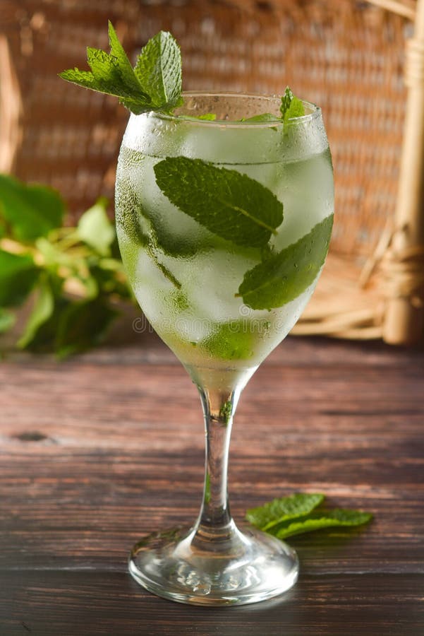 Summer cocktail drink in wine glass. Refreshing drink with mint leaves, gin tonic, syrop. Wooden background