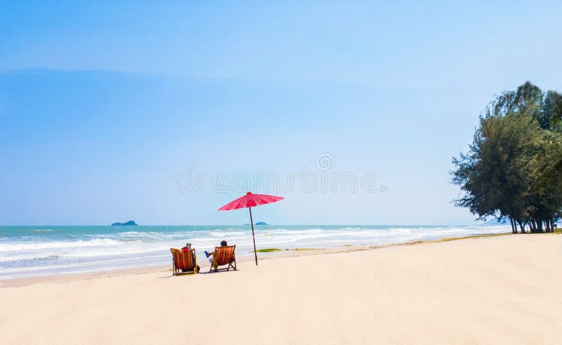 summer couple of Middle-aged 40-50s on the beach vacation holiday relax on their chairs under a red umbrella. travel concept at stock image summer couple of Middle-aged 40-50s on the beach vacation holiday relax on their chairs under a red umbrella. travel concept at stock image