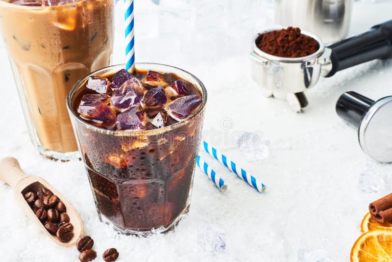 Summer drink iced coffee or soda in a glass and ice coffee with cream in a tall glass surrounded by ice.