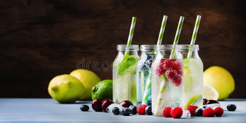 Summer drinks set. Berry, fruit and citrus non-alcoholic refreshing ice cold beverages and cocktails in glass bottles on blue