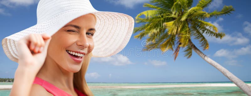 Beautiful smiling woman in sun hat on beach.