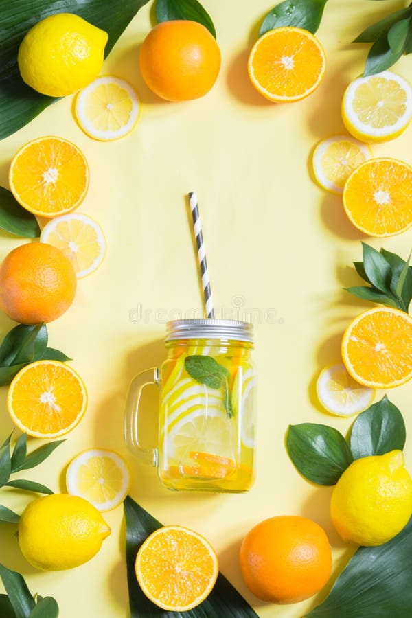 Summer fruits water with lemon, orange, mint and ice in mason jar on yellow. Tropical concept. stock images Summer fruits water with lemon, orange, mint and ice in mason jar on yellow. Tropical concept. stock images