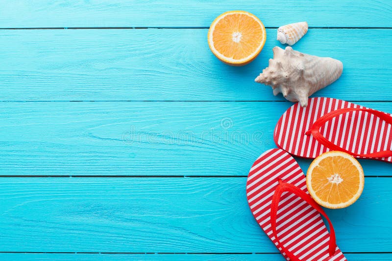 Summer fun time and flip flops. Sea shell. Slippers and orange fruit on blue wooden background. Mock up and picturesque. Top view.