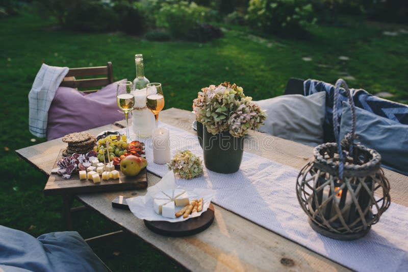 Summer garden table decorated with flowers and candles, evening party with wine