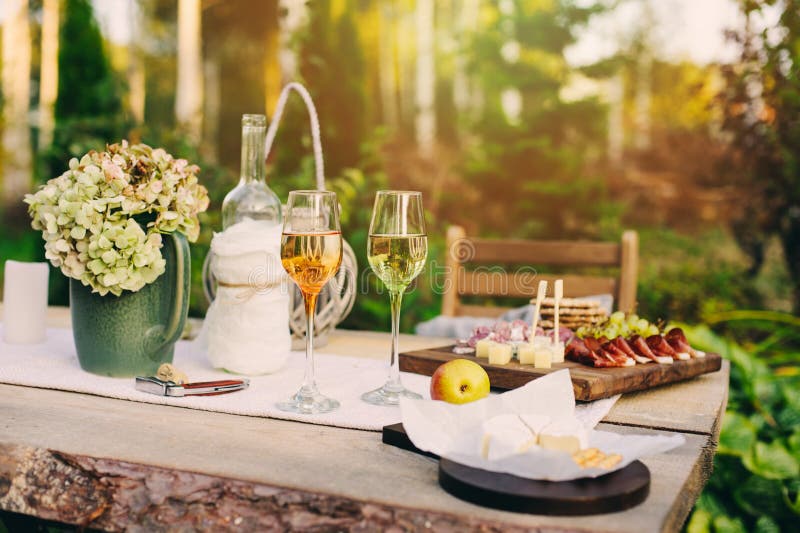 Summer garden table decorated with flowers and candles, evening party with wine