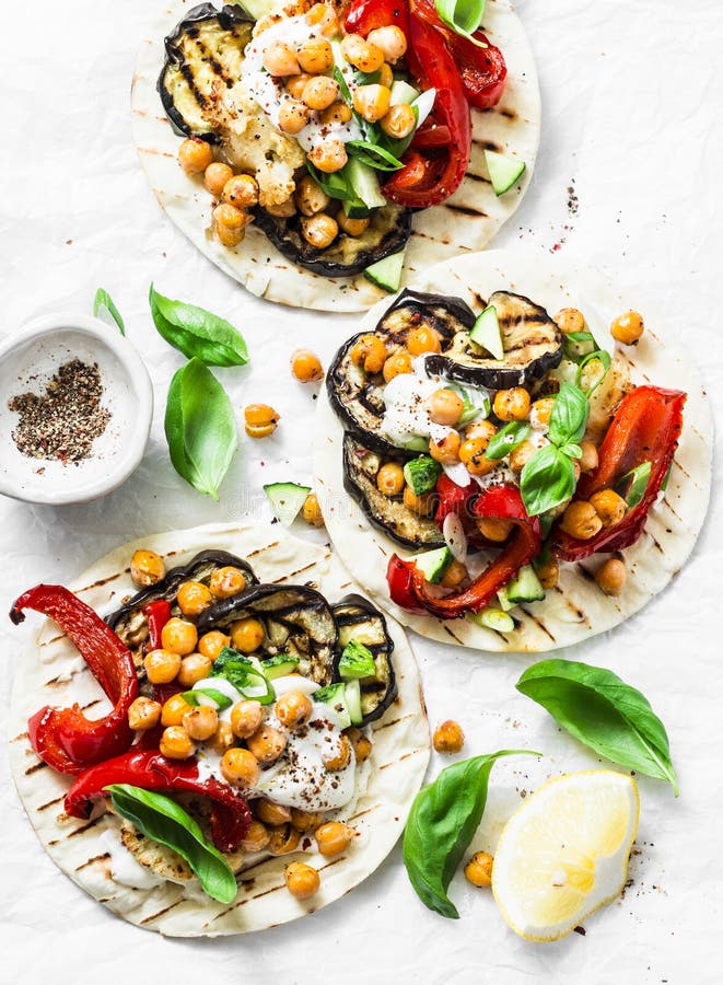 Summer grilled garden vegetables and spicy chickpeas vegetarian tortillas on a light background, top view. Healthy food picnic