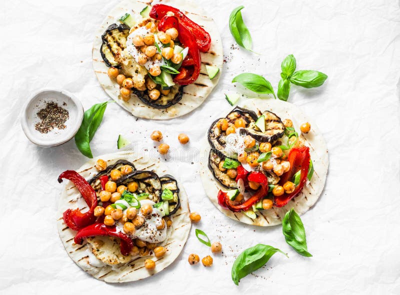 Summer grilled garden vegetables and spicy chickpeas vegetarian tortillas on a light background, top view. Healthy food