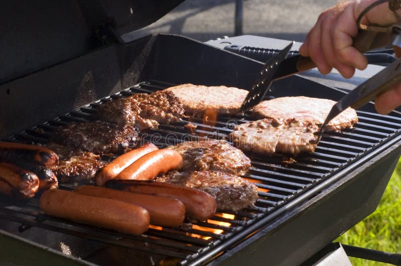 Párky v rohlíku a hamburgery na grilu na letní grilovačku.