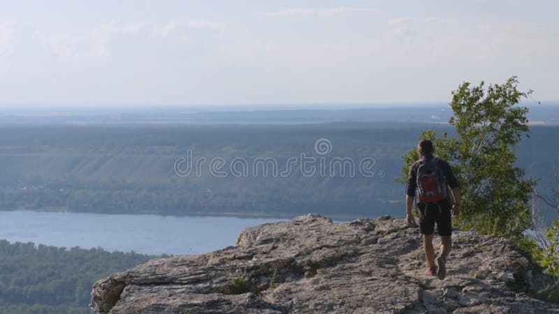 Summer Hiking in the mountains. A young man climbs the mountain. Raises his hands in a sign of victory over their fears and diffic stock video footage Summer Hiking in the mountains. A young man climbs the mountain. Raises his hands in a sign of victory over their fears and diffic stock video footage