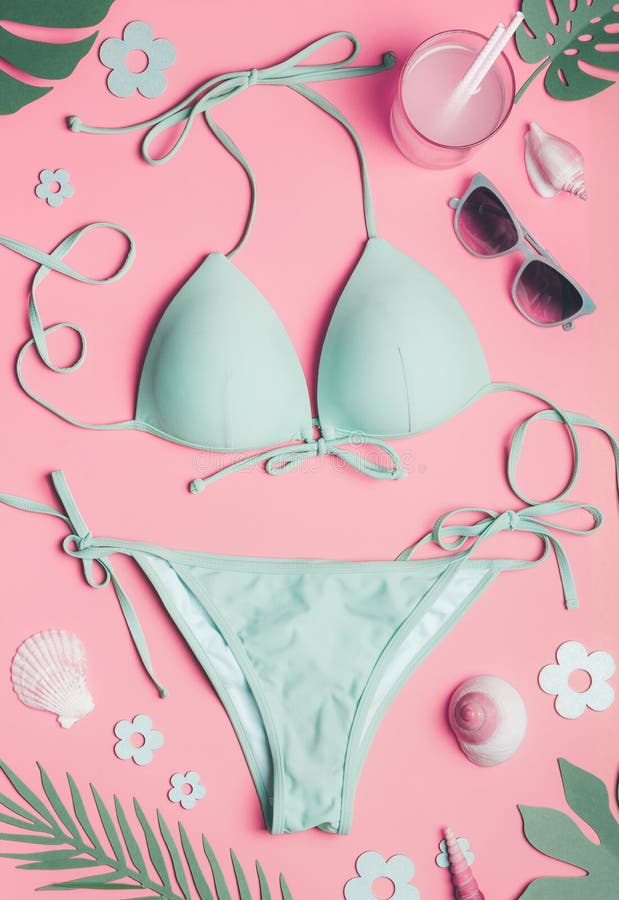 Summer holiday concept with bikini, sunglasses , sea shells and tropical leaves on pastel pink background, top view. Flat lay.