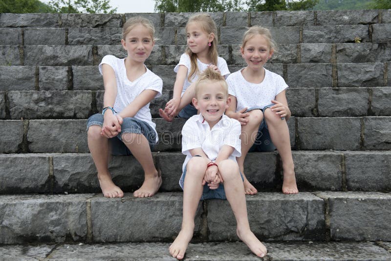 Summer holidays: children with a book seated outdoors on stairs