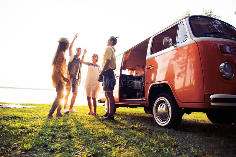 Summer holidays, road trip, vacation, travel and people concept - smiling young hippie friends having fun over minivan royalty free stock images Summer holidays, road trip, vacation, travel and people concept - smiling young hippie friends having fun over minivan royalty free stock images