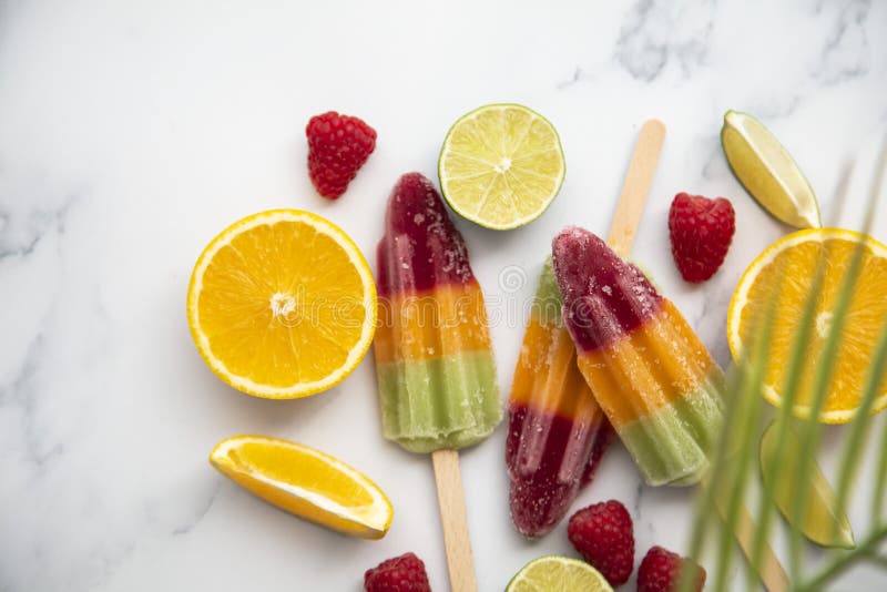 Summer ice lollies with fruit and a tropical palm leaf