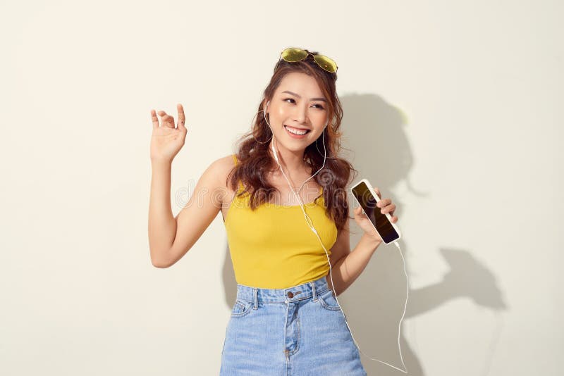 Summer lady. Beautiful asian girl singing and dancing while listening to music on white background