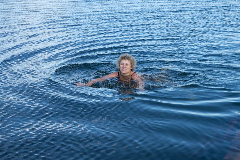 An elderly woman is swimming in the blue water. stock image An elderly woman is swimming in the blue water. stock image