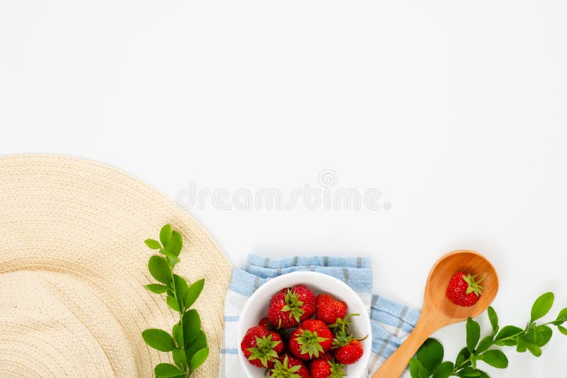 Summer morning breakfast concept with strawberry in bowl, straw hat, barberry branches on white background. Flat lay, top view