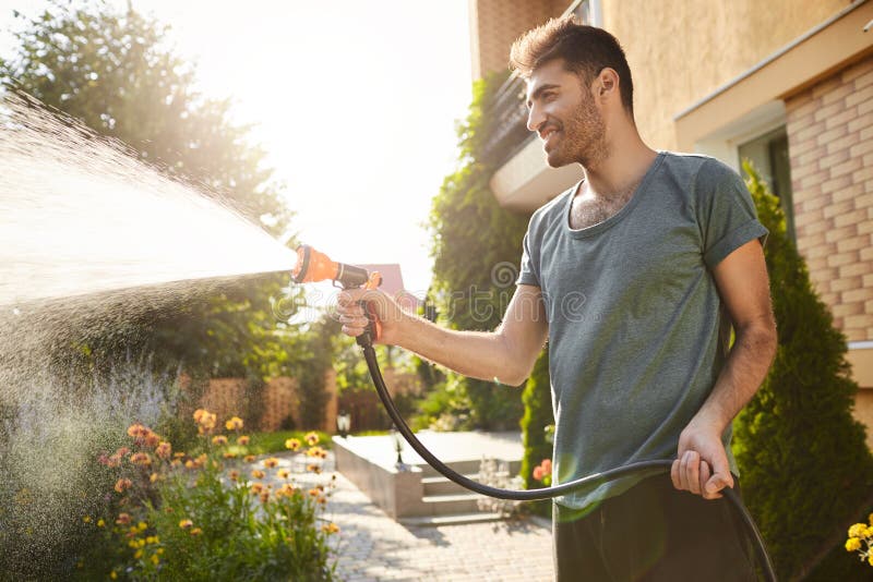 Summer morning in countryside house. Portrait of young attractive tan-skinned bearded man in blue t-shirt smiling stock image Summer morning in countryside house. Portrait of young attractive tan-skinned bearded man in blue t-shirt smiling stock image