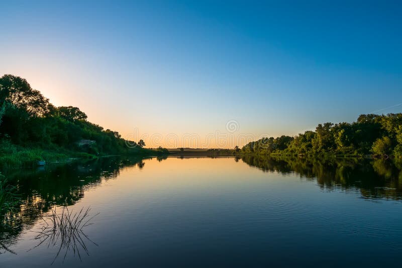 Summer nature panorama at sunset, forest trees and river with reflection in water, vivid tranquil and relax background stock photo