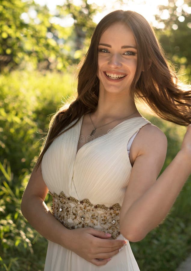 Summer portrait of young beautiful lady wearing long white evening dress posing in the park. royalty free stock photo Summer portrait of young beautiful lady wearing long white evening dress posing in the park. royalty free stock photo